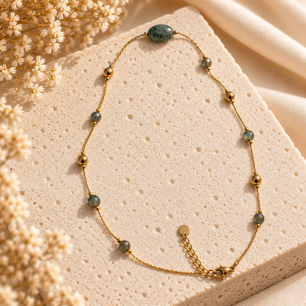 Collier à chaîne dorée, perles vert sauge et ovale central turquoise veiné, présenté à plat.